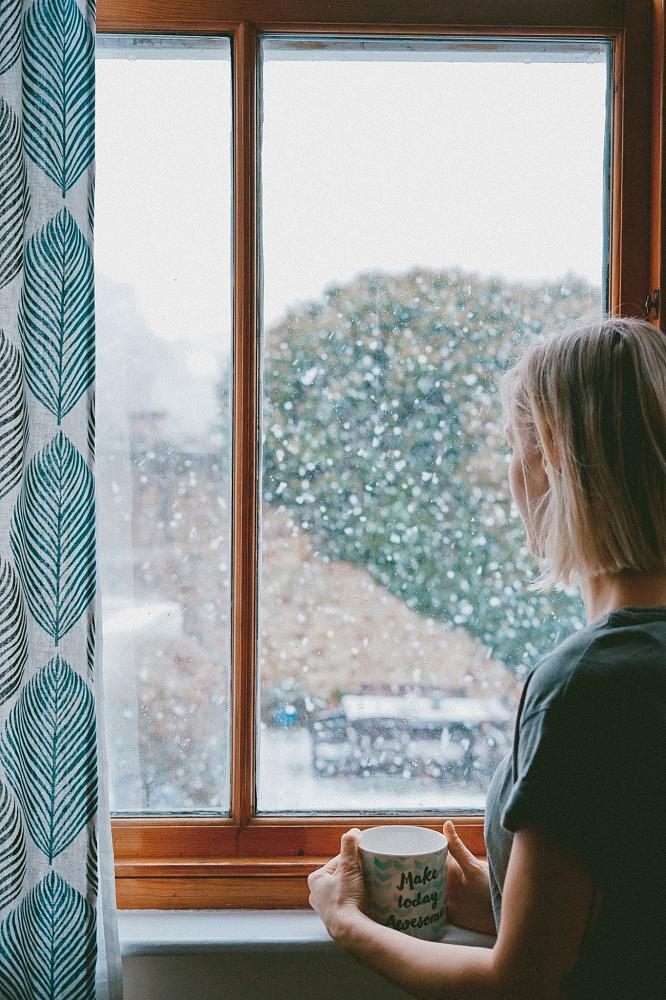 A woman looking at the window in deep thought.