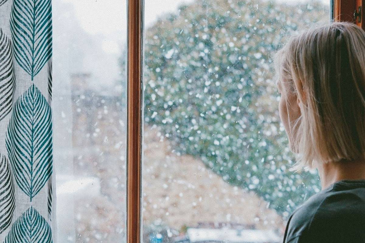 A woman looking at the window in deep thought.