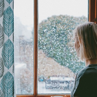A woman looking at the window in deep thought.