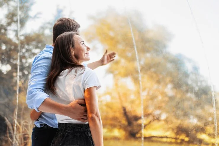 Hugging couple inside transparent bubble tent glamping nature background
