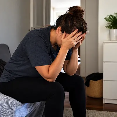 Stressed person sitting alone with head in hands